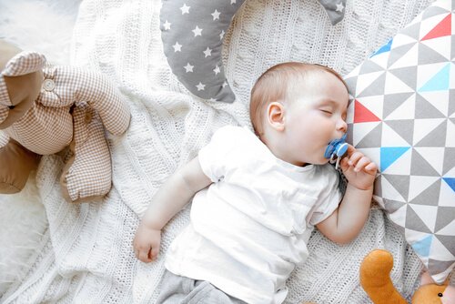 Dziecko śpiące na plecach ze smoczkiem w ustach, uczące się jak przespać całą noc