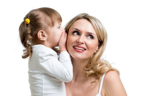 Mała dziewczynka szepcząca mamie do ucha