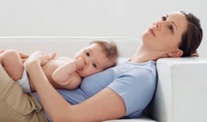 Zmęczona mama leży na kanapie z dzieckiem