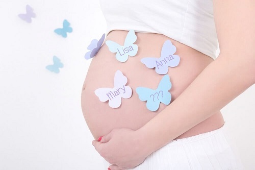 Brzuch w ciąży z przyklejonymi motylkami z imionami dzieci