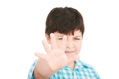 Chłopiec wyciągający przed siebie rękę w geście "stop"