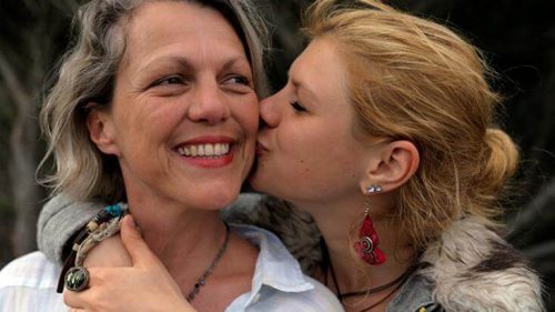 Dorosła córka całuje mamę w policzek