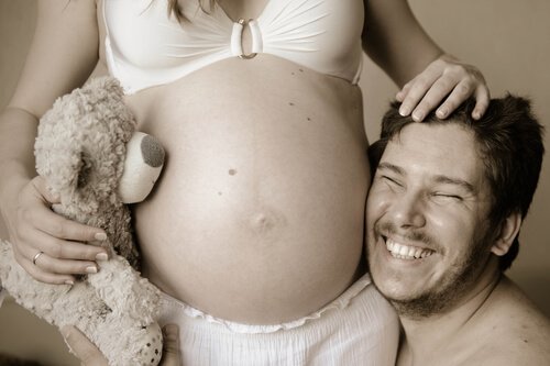 Kobieta w ciąży, uśmiechnięty mężczyzna i pluszowy miś - jak przygotować się na poród