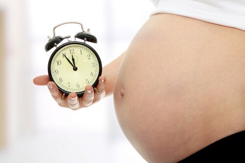 Mama w ciąży trzyma budzik