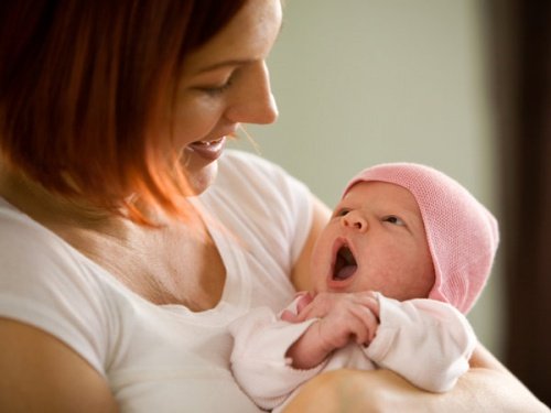 Mama uśmiechająca się do przytulanego niemowlaka