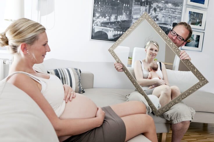 Mama w ciąży przeglądająca się w lustrze trzymanym przez tatę