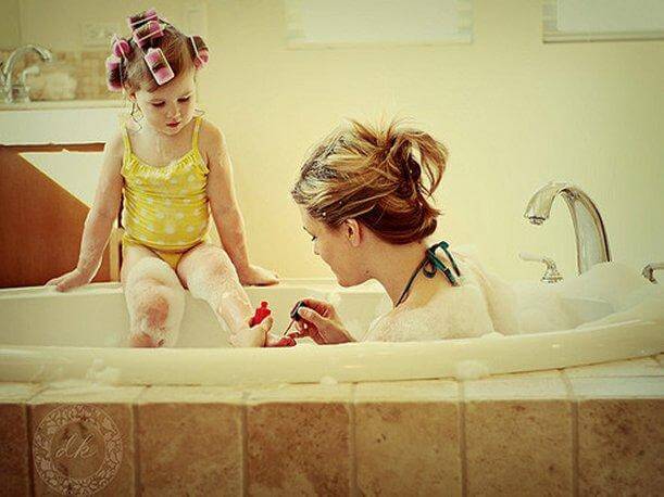 Mama w wannie malująca paznokcie u stóp córki siedzącej na rancie wanny