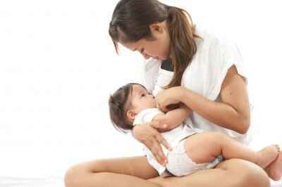 Siedząca mama karmiąca dziecko piersią - karmienie piersią po cięciu cesarskim