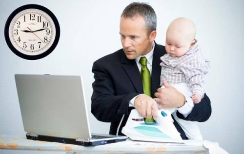 Tata w garniturze pracujący na komputerze z dzieckiem na rękach