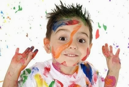 Uśmiechnięty chłopiec pomazany kolorowymi farbami