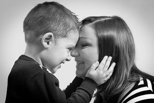 Uśmiechnięty chłopiec przyciskający czoło do czoła mamy