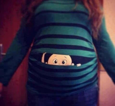 Brzuch w ciąży z wyglądającym z niego dzieckiem