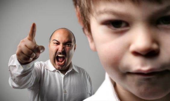 Chłopiec w tle krzyczący na niego tata - tak zachowują się toksyczni rodzice