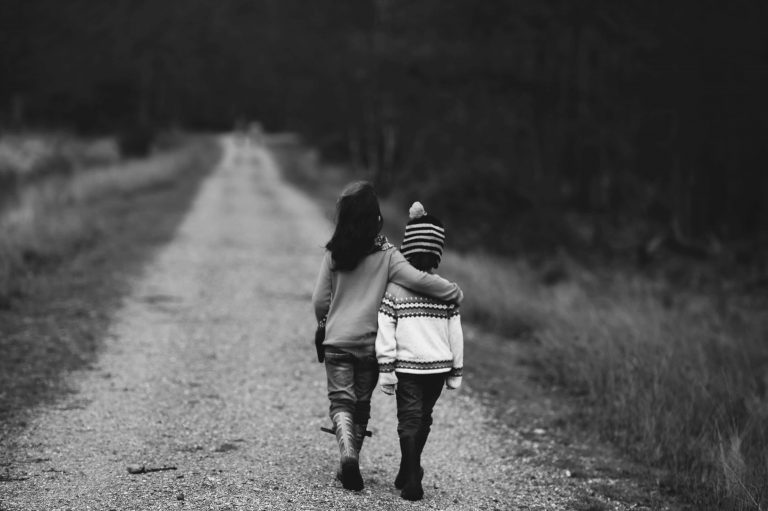Dwoje przytulonych dzieci idących razem drogą