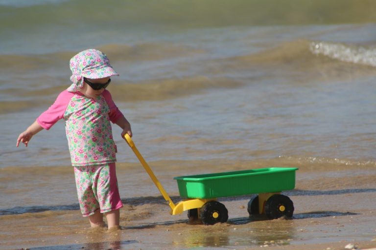 Dziecko ciągnące wózek po brzegu morza