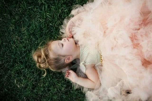 Dziewczynka w tiulowej sukience leżąca na trawie