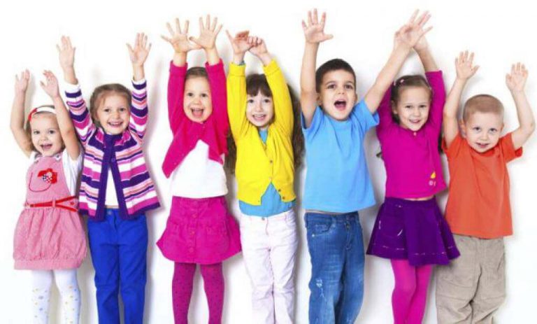 Grupa śmiejących się dzieci stojąca w rzędzie z rękoma wyciągniętymi do góry - ćwiczenia uczące czym jest świadomość emocjonalna