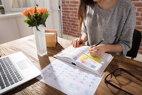 Kobieta siedząca przy stole, tworząca grafik w kalendarzu