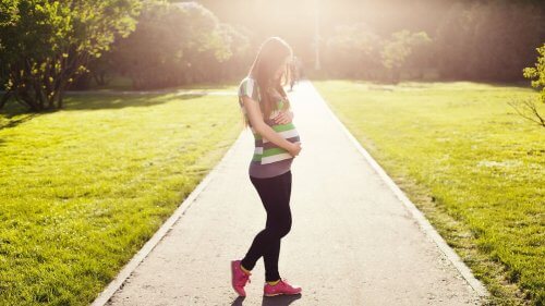 Kobieta w ciąży obejmująca brzuch na ścieżce w parku