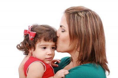 Mama całująca trzymaną na rękach córkę w czoło