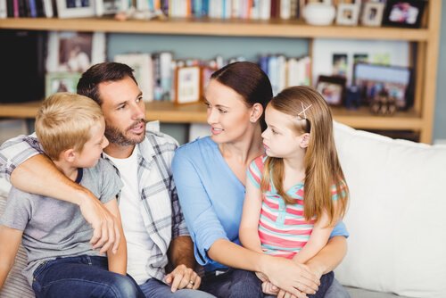 Mama i tata siedzący z córką i synem na kolanach na kanapie