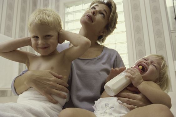 Mama spoglądająca z rozpaczą w górę, przytulająca dwójkę płaczących dzieci
