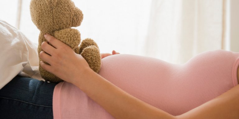 Mama trzymająca pluszowego misia na brzuchu w ciąży - w którym tygodniu ciąży jesteś?
