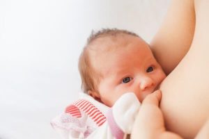 Małe niemowlę spożywające pokarm matki