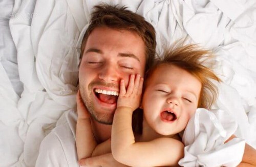 Ojciec bawiący się z córką w łóżku