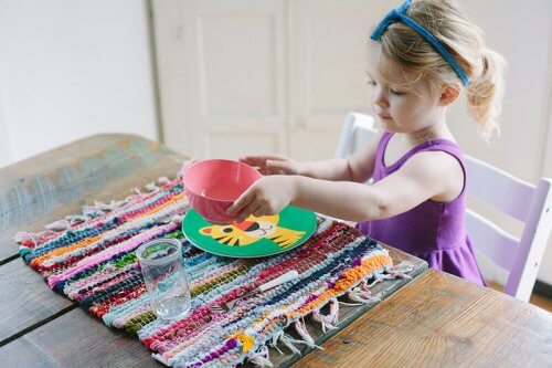 Przydzielenie dzieciom obowiązków domowych - dziewczynka nakrywa stół