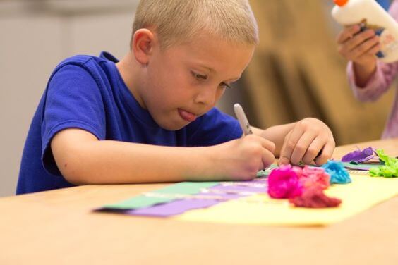 Rysujący, skoncentrowany chłopiec wystawiający język - wystawianie języka podczas rysowania