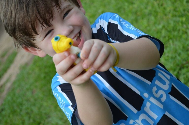 Śmiejący się chłopiec celujący wodnym pistoletem w obiektyw - jak pracuje mózg dziecka podczas zabawy