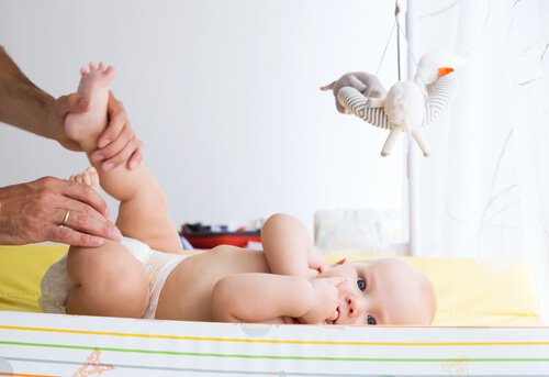 Spokojne dziecko leżące na przewijaku - zmienianie pieluszek