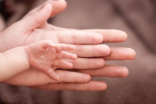 Trzy dłonie nałożone na siebie: mamy, taty i dziecka - rodzenie chłopca boli bardziej niż rodzenie dziewczynki