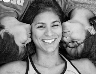 Uśmiechnięta mama leżąca między dwoma synami - małe rzeczy, które można zrobić dla dziecka