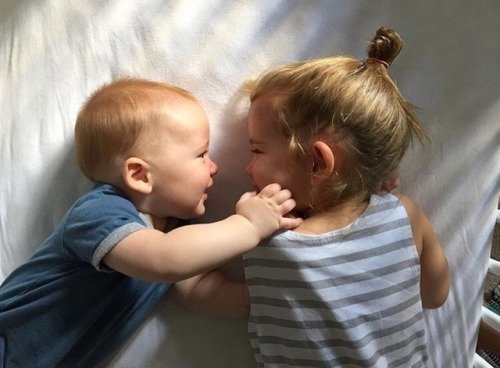 Dziewczynka i chłopiec przytulający się leżąc na łóżku - rozwijanie inteligencji emocjonalnej