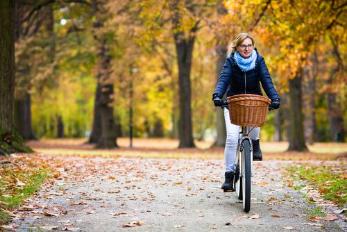 Kobieta jadąca na rowerze po jesiennym parku