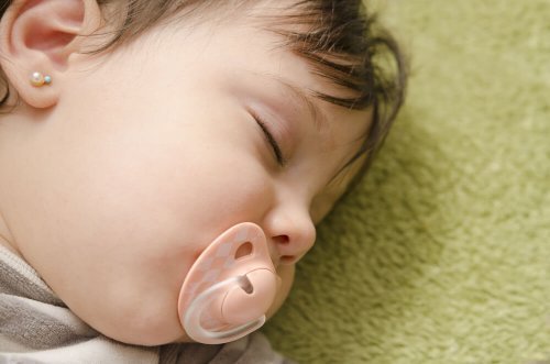 Kolczyki dla niemowląt - dziewczynka śpi ze smoczkiem