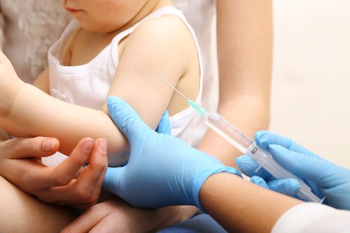 Lekarka trzymająca strzykawkę ze szczepionką i rączkę dziecka - co może pomóc dziecko zwalczyć ostre zapalenie oskrzelików