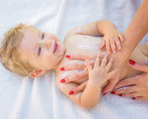 Mama smarująca klatkę piersiową dziecka kremem