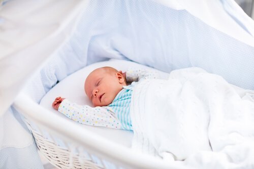 Noworodek śpiący w białej kołysce - pierwszy miesiąc życia dziecka to głównie sen i jedzenie