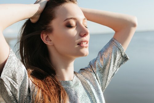 Relaksująca się kobieta z zamkniętymi oczami i dłońmi we włosach