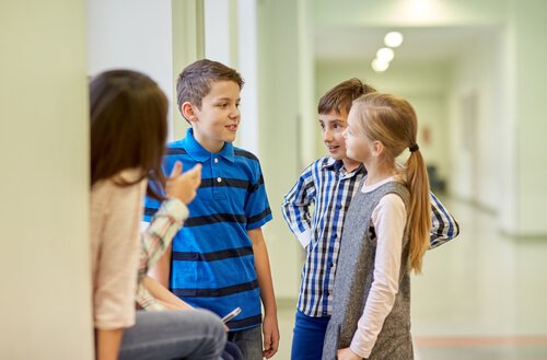 Dwóch chłopców i dwie dziewczynki rozmawiający na szkolnym korytarzu