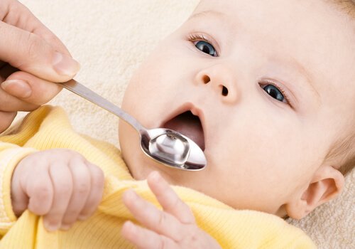 Mama ppodająca dziecku lekarstwo na łyżeczce - zapobieganie grypie