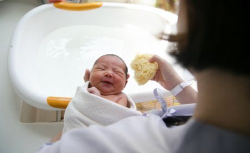 Pierwsza kąpiel noworodka - dziecko owinięte w ręcznik