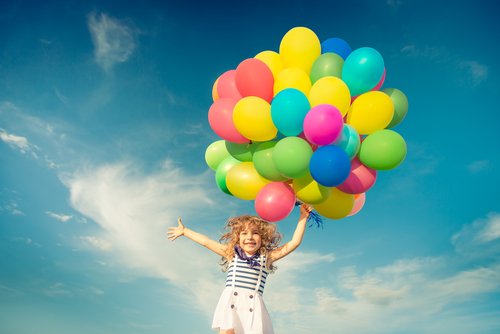 Dziewczynka skacze trzymając kolorowe balony