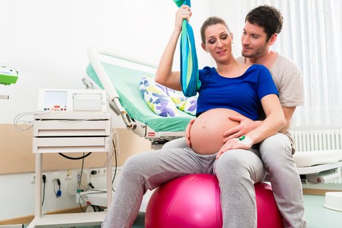 Kobieta w ciąży siedząca razem z partnerem na dmuchanej piłce - pozycje do porodu