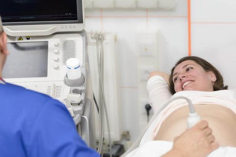 Uśmiechnięta kobieta w ciąży podczas badania USG