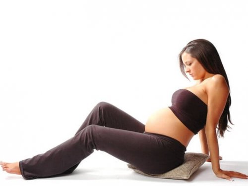 Kobieta w ciąży siedząca na poduszce, wykonująca ćwiczenia miednicy