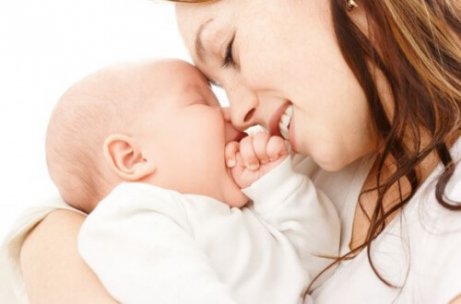 Uśmiechnięta mama dotykająca czołem czoła niemowlęcia